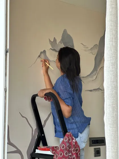 A quiet moment on a stepladder, painting a mountain mural. Art and life move in a quiet rhythm, and in the simplicity of lines and colors, we find truths too soft for words.