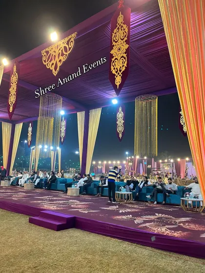A luxurious lounge area with deep purple carpeting, teal sofas, and ornate gold hanging decor, creating a rich and royal ambiance.