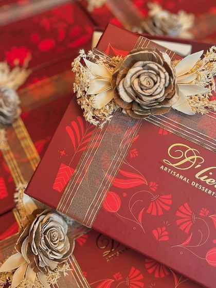 A detailed shot of the elegant sola wood flower and ribbon detail on our premium red Diwali gift box.