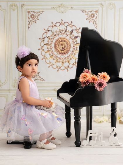 A little girl sits at a miniature piano, a classic and timeless portrait setup that is always a favorite.