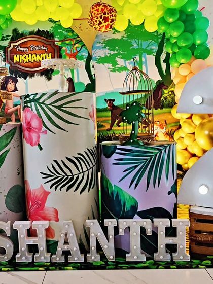 A full view of a Jungle Book-themed second birthday. The setup includes a character backdrop, themed plinths, and a large light-up number '2'.