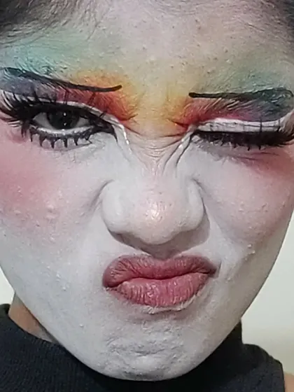 A close-up on the details of the clown makeup, including the textured white base and the blended rainbow colors.