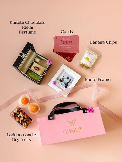 A flat lay of our pink Rakhi hamper, showcasing the thoughtful curation of gifts like a watch box, photo frame, laddoo candles, and dry fruits.