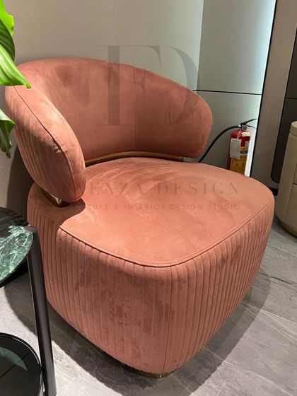This armchair in a soft peach-colored velvet features a pleated back and a metal-accented base. It's a beautiful example of combining soft textures with strong, modern details.