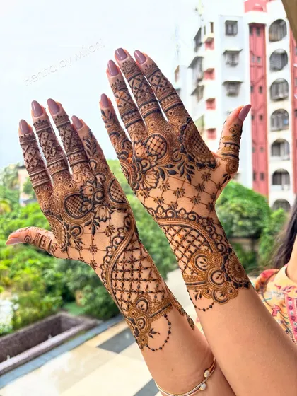 This Arabic-fusion bridal design combines bold floral vines with delicate net patterns. The open spaces make the intricate details pop, creating a modern yet traditional look.