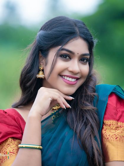 A close-up portrait focusing on the model's expressive face and the details of her traditional earrings and half saree.