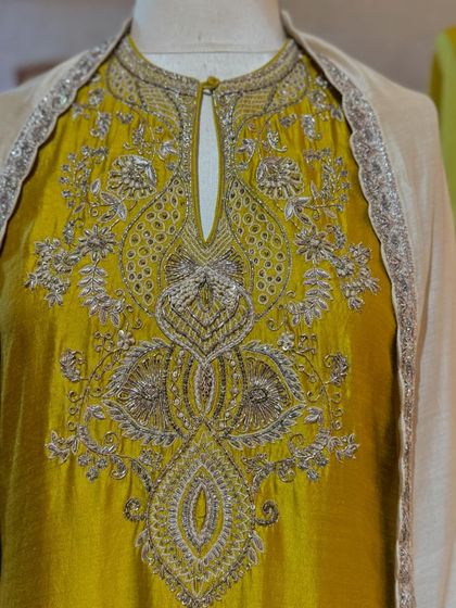 A close-up of the incredibly detailed silver zardozi work on the yoke of a mustard yellow kurta.