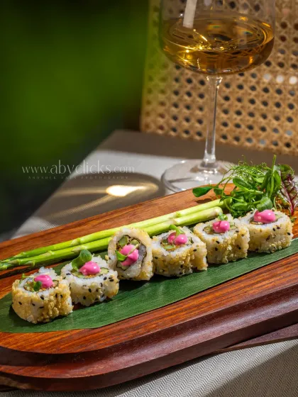 Colorful sushi rolls on a wooden platter, paired with a glass of white wine at Camo, Noida.