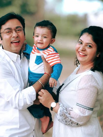 A joyful family photo, capturing the laughter and happiness of the parents playing with their little boy outdoors.