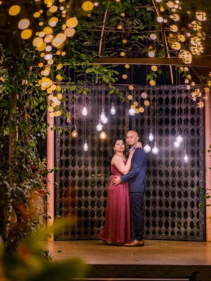 A wide shot of the rustic gate and hanging bulb installation, creating a beautiful and moody atmosphere for a couple's portrait.