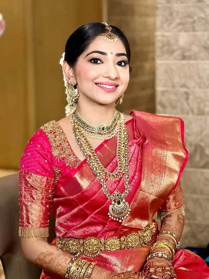 A smiling portrait of a happy South Indian bride. Her hair is pulled back into a neat bun with flowers, and the makeup is tailored to enhance her natural beauty.