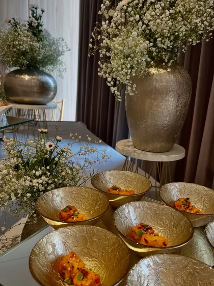 A beautifully styled buffet table for an anniversary, featuring our Spicy Pizza Paneer Paprika Dip and other dishes, framed by elegant silver vases of baby's breath.