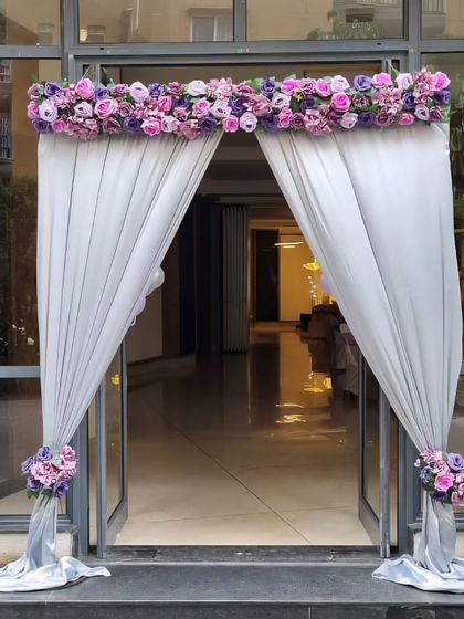 A beautiful floral and drape entrance decoration in shades of purple and lavender, perfect for a wedding or engagement party.