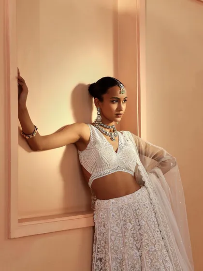 This look features a stunning all-white embroidered lehenga. I styled it with a maang tikka and a layered necklace to create a modern yet traditional bridal look, perfect for a summer wedding.