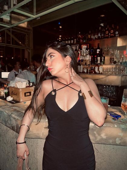 A classic shot at the bar in a little black dress with unique strap details. This is a timeless look that's always in style.