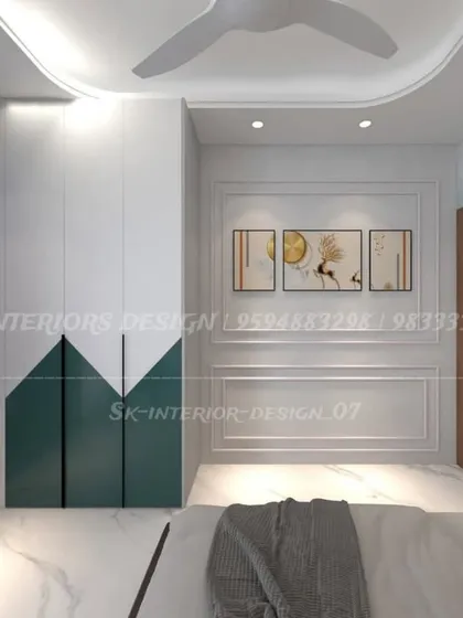 A bedroom featuring a two-tone hinged wardrobe in white and dark green. The classic wall molding adds a touch of elegance to the modern furniture.