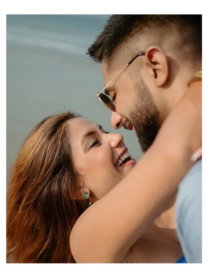 A sweet, close-up portrait from a beach engagement session. The focus is on the couple's expressions and the clear joy they share.