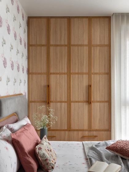 This primary bedroom radiates tranquility with its soothing palette of mauve grey and pastel green. The tuck-in wardrobe features soft wood tones and elegant grooved details for a touch of classic charm.