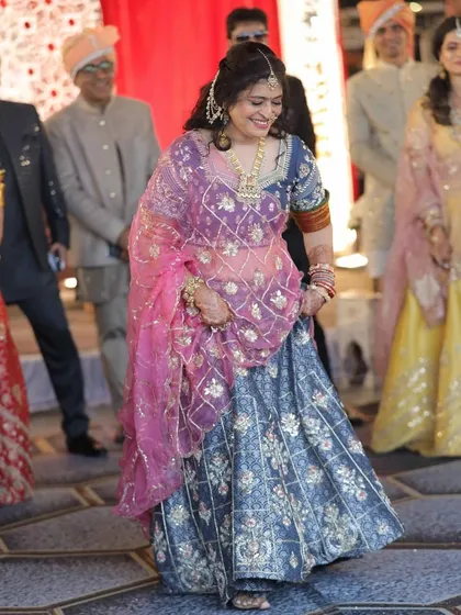 Our client enjoying a wedding celebration in a custom-designed blue printed lehenga, paired with a bright pink embroidered dupatta for a beautiful contrast.