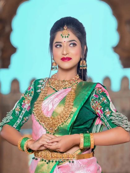 A full view of the model, showing how the grand jewellery complements the pink and green saree.