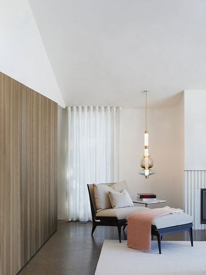 A single Luna pendant adds a touch of sophistication to a cozy reading corner, its warm light perfect for a relaxing evening.