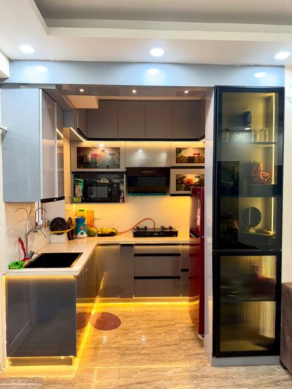 This compact U-shaped kitchen is packed with storage. We used a cool grey laminate and added a tall glass-fronted pantry unit for extra storage.