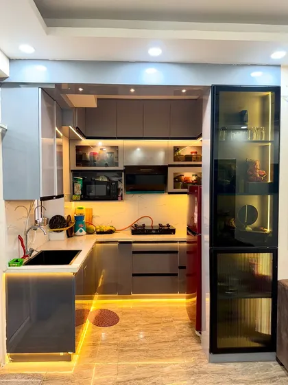 This compact U-shaped kitchen is packed with storage. We used a cool grey laminate and added a tall glass-fronted pantry unit for extra storage.