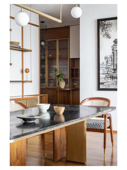 A detail of the dining area, with custom cane-back chairs and a heavy stone-topped table. The modern light fixture and artwork complete the sophisticated look.