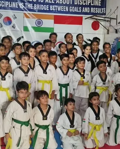 A large group photo of our students after a belt promotion ceremony, showcasing a wide range of belts from yellow to black.