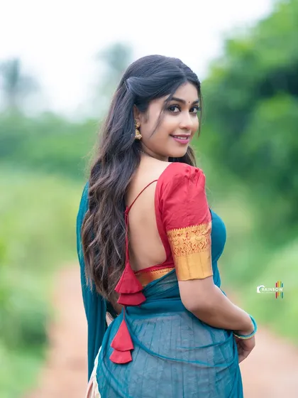 This shot from the back highlights the beautiful design of the blouse and the way the half saree is draped, set against a lush green path.