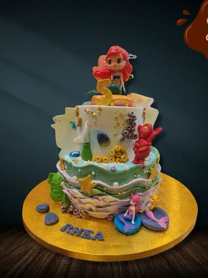 A smaller, yet detailed mermaid-themed cake perfect for an intimate celebration. It features an Ariel topper and is decorated with fondant coral, starfish, and other sea treasures.