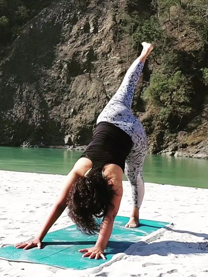 A one-legged downward dog stretch by the river. This variation, Eka Pada Adho Mukha Svanasana, opens the hips and lengthens the hamstrings while building upper body strength.