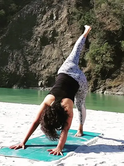 A one-legged downward dog stretch by the river. This variation, Eka Pada Adho Mukha Svanasana, opens the hips and lengthens the hamstrings while building upper body strength.