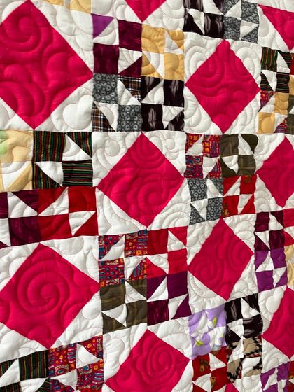 A close-up of the patchwork quilt, showing the swirling quilting pattern in the pink diamonds.