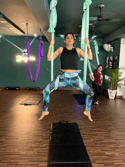 Finding balance and strength in the air. This member holds a steady pose, demonstrating the focus and bodily awareness that develops through consistent aerial yoga practice.