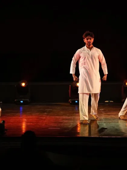 Three dancers command the stage with strong, grounded poses in our "Inquilab" production. This demonstrates our choreography for male performers, focusing on powerful and expressive movements.