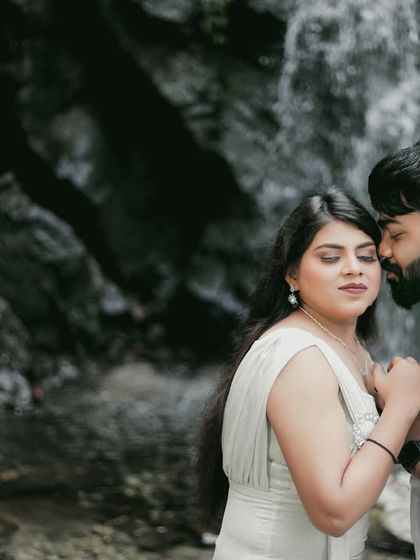 A close-up, intimate moment by the waterfall. This shot captures the quiet affection and trust between the couple in a beautiful natural setting.
