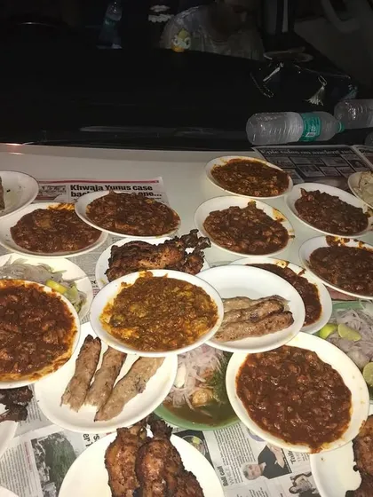 A close-up of a feast served on a car bonnet. This is what late-night cravings in Mumbai look like, with plates of Bheja Fry, kebabs, and Tangdi filling up every inch of space.