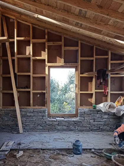 Inside one of the Vasudev guesthouses, the timber frame structure is exposed. This honest expression of construction shows the interplay between the stone foundation and the wooden roof system, which is designed for the local climate.