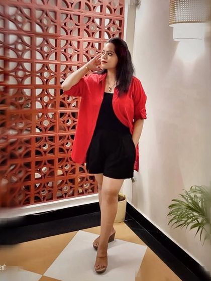 A bright red shirt layered over a black romper creates a striking color-blocked look. This is a powerful way to use color to express confidence in a smart casual context.
