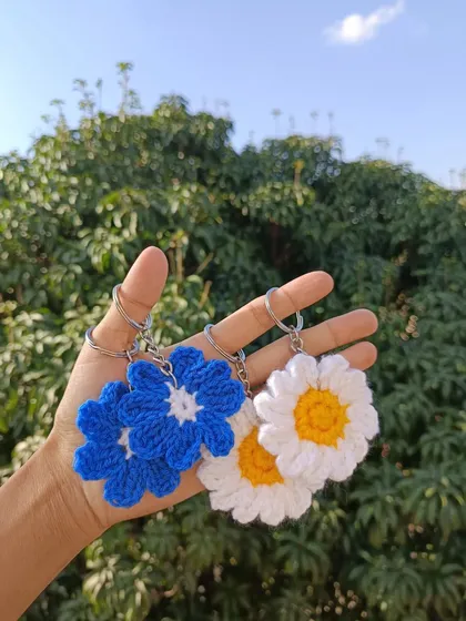 A handful of daisy keychains in vibrant blue and classic white. These floral charms are perfect for spring and summer collections.