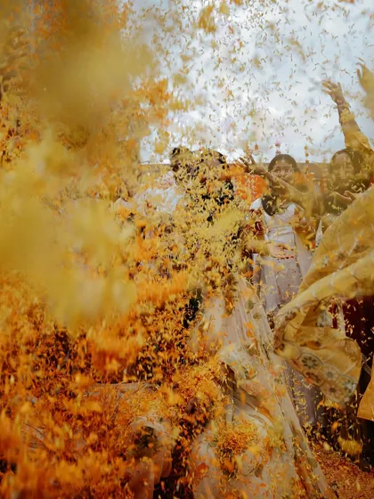 An explosion of joy and marigold petals. This action shot freezes a moment of pure, uninhibited celebration during a Haldi ceremony, embodying the vibrant, chaotic, and unforgettable fun of Indian pre-wedding festivities.