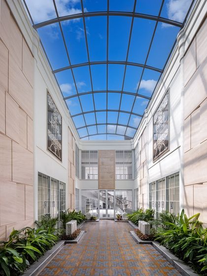 Another view of the glass-roofed courtyard in The Grand Alabaster, showcasing how it transforms the central corridor into a sun-drenched gallery. Lined with lush plants, it feels as though the sky is part of the home, blurring the line between inside and out.