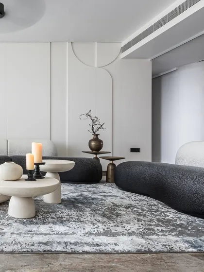 I love to play with form and flow. This living room uses bold, curvy furniture in a sleek black-and-white palette to create a dynamic yet inviting social hub. The sculptural silhouettes and circular stone tables create a rhythm that is modern and full of personality.