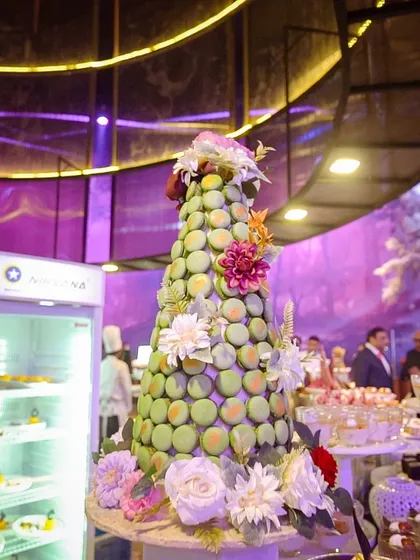 A close-up of a stunning pistachio macaron tower, decorated with delicate sugar flowers. A true work of pastry art.