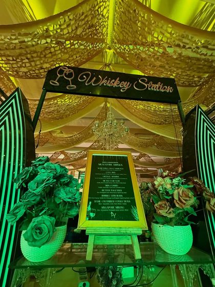 Another look at our custom 'Whiskey Station' menu board, set against a backdrop of green-lit floral decor.