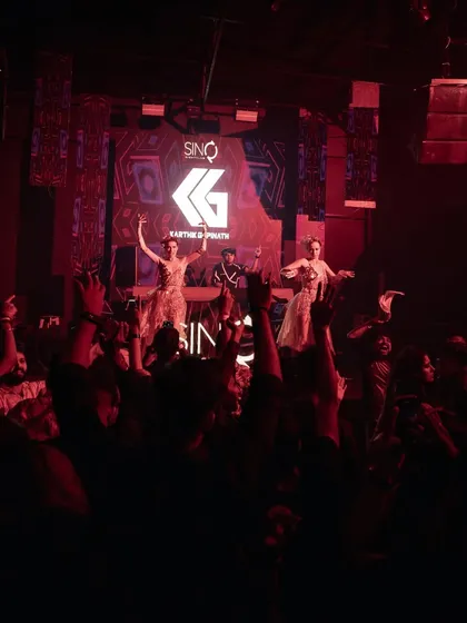 A massive crowd with hands up, with dancers on stage adding to the spectacle in Goa.