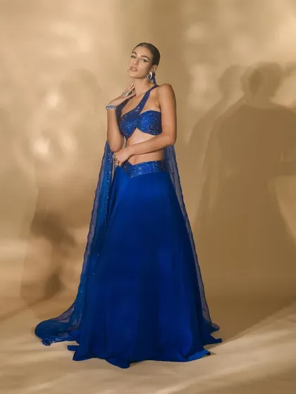 A lookbook image for Nikhil Thampi's 'Sapphire Edit'. The model's pose is designed to showcase the entire ensemble, including the sheer, embellished cape and flowing skirt.