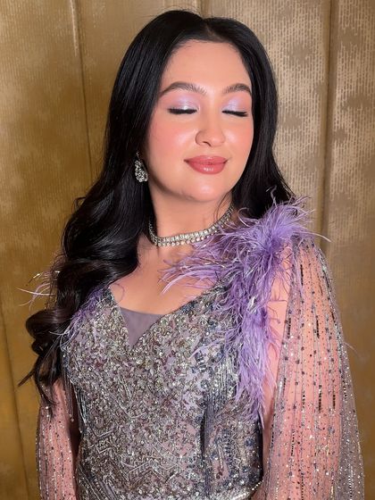 A close-up of this dreamy cocktail glam. The look features a wash of lavender eyeshadow and glass-like skin, accented by a feathered gown for a touch of high-fashion elegance.
