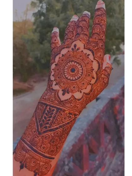 This bridal design is centered around a large, intricate mandala on the back of the hand, with detailed patterns extending up the arm and down the fingers.